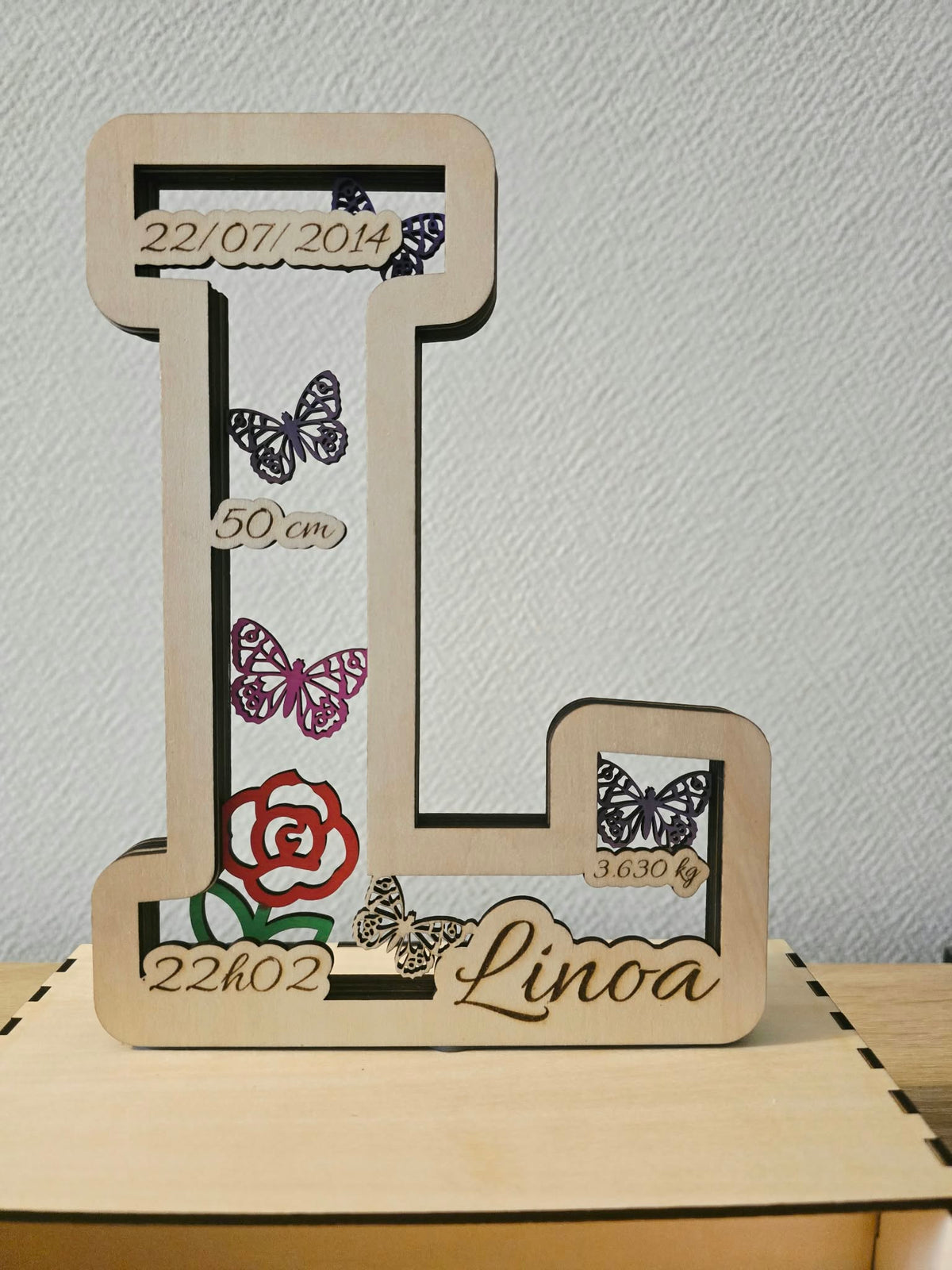 Détail de la lettre de naissance L avec prénom, informations de naissance et papillons